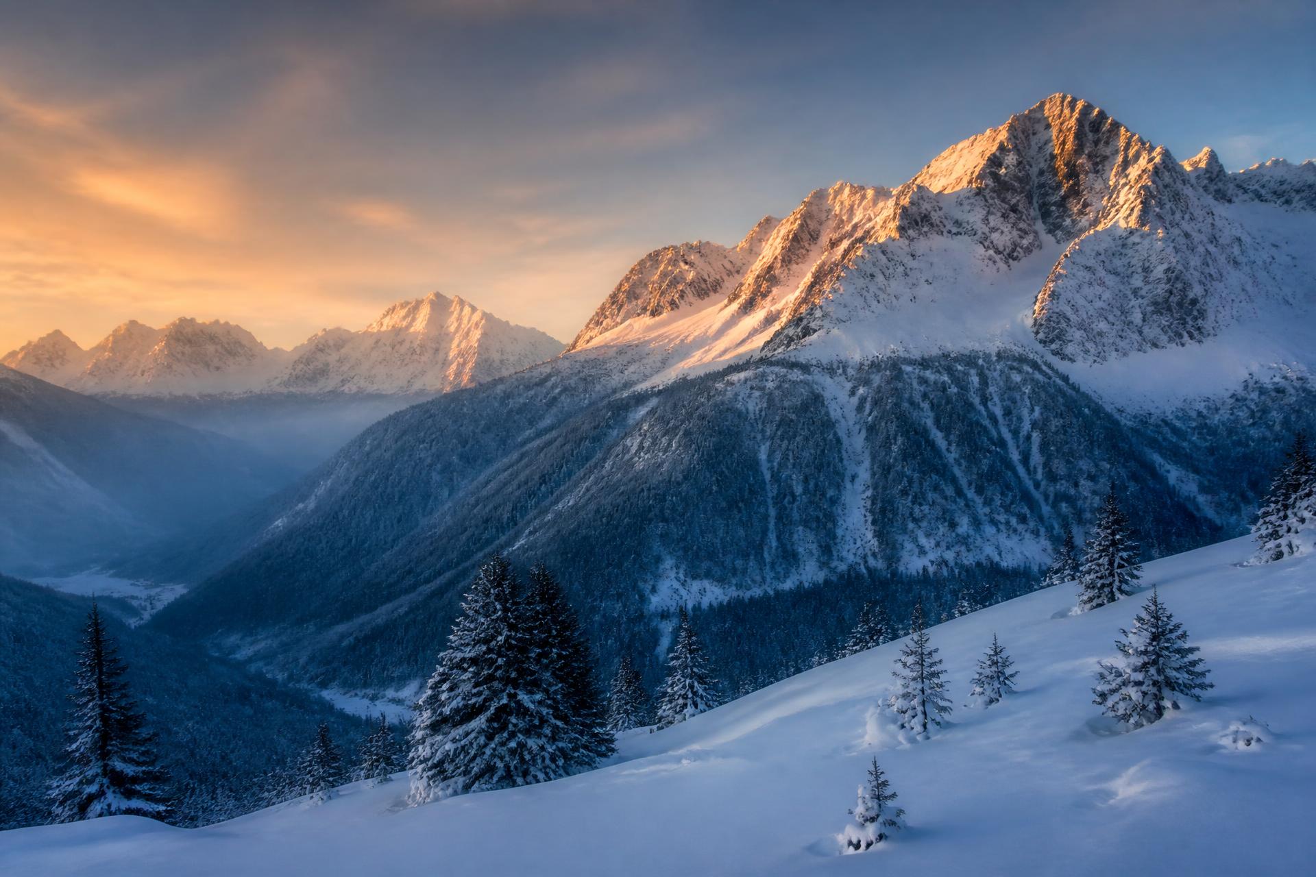 Snow-covered Alpine peaks catching the last of the evening sun